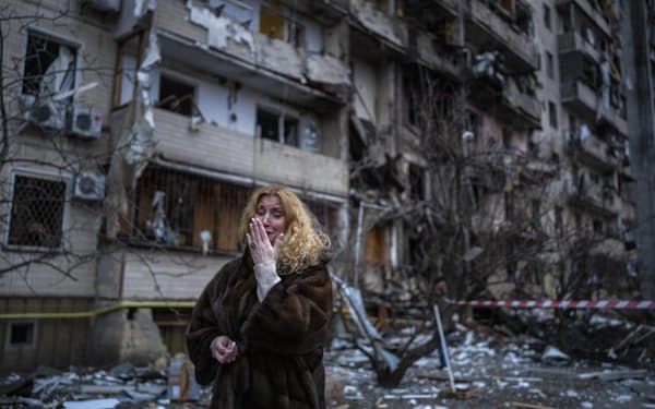 　25日、ウクライナの首都キエフで、砲弾を受けた自宅脇に立つ女性（AP＝共同）
