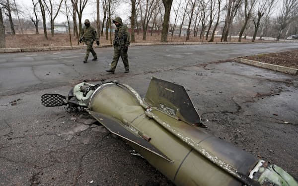 Militants of the self-proclaimed Donetsk People's Republic inspect the remains of a missile that landed on a street in the separatist-controlled city of Donetsk, Ukraine February 26, 2022. REUTERS/Alexander Ermochenko