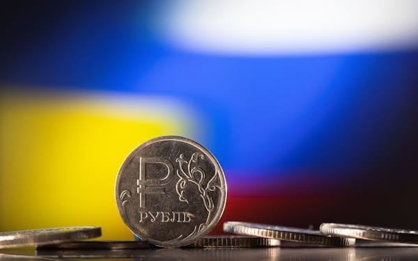 Russian Rouble coins are seen in front of displayed Ukrainian's and Russia's flag colours in this illustration taken, February 24, 2022. REUTERS/Dado Ruvic/Illustration