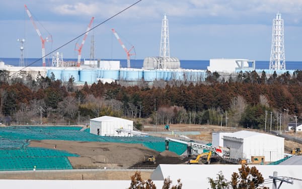 福島県大熊町にある除染土などの中間貯蔵施設(手前)。後ろは福島第1原子力発電所構内に並ぶ貯水タンク(2月24日)