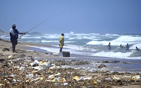 プラスチックごみに覆われた砂浜。釣りをする人の姿も見られた（南アフリカ東部ダーバン）＝共同