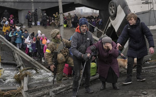 ロシア軍の攻撃で壊された橋の下を通り避難するウクライナの人々(5日、キエフ近郊)=AP