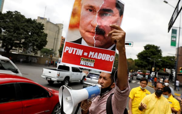 ロシアのプーチン大統領とベネズエラのマドゥロ大統領の顔写真を組み合わせたポスターを掲げ、ウクライナ侵攻に抗議するカラカスの市民ら（4日）＝ロイター