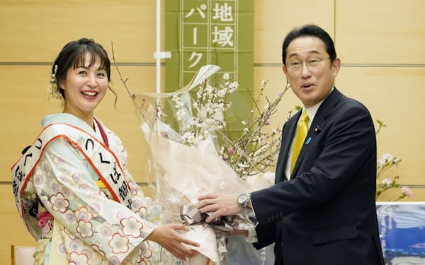 　つくば観光大使（左）から紅白の梅を贈られる岸田首相（8日、首相官邸）＝共同