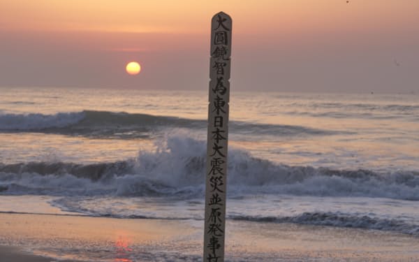 犠牲者を供養する卒塔婆の立つ海岸に昇る3月11日の日の出（福島県浪江町）