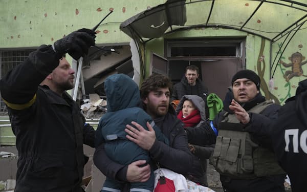 砲撃を受けた産科病院から子どもを抱えて逃げる市民ら（9日、ウクライナ南東部マリウポリ）=AP