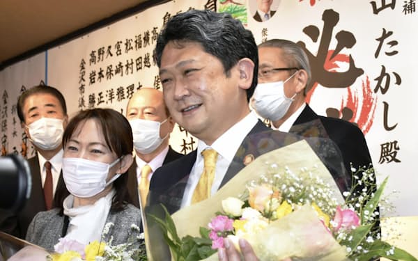 金沢市長選で初当選を決め、花束を手に笑顔を見せる村山卓氏（手前右、13 日夜）＝共同