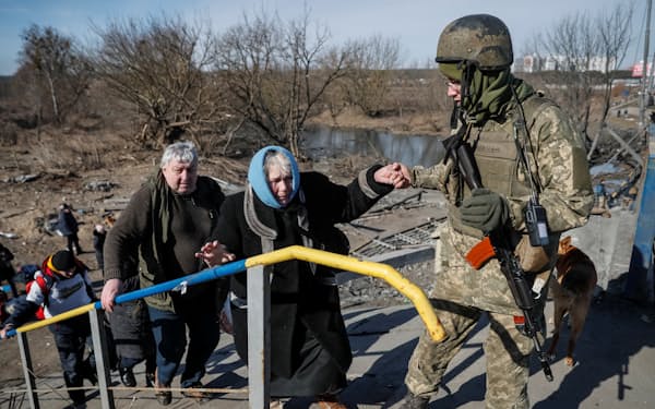 ウクライナ軍兵士に助けられ、イルピンから避難しようとする住民ら（12日）＝ロイター