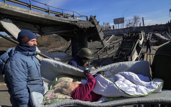 11日、ウクライナ・キエフ近郊イルピンで高齢者を避難させる人々（AP）