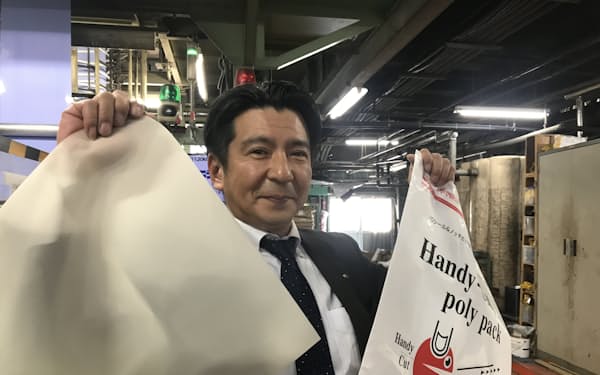 廃棄米由来のバイオマスプラスチックを使った包装袋（左）を手にする平川浩太郎社長