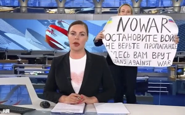 ロシアのテレビの生放送中にキャスターの背後で「戦争をやめて」などと書いた紙を掲げる女性(ウクライナのポドリャク大統領府長官顧問のツイッターから)=共同
