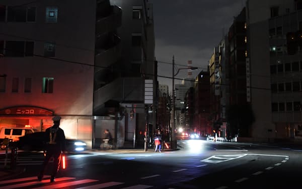 停電した東京都港区の交差点で警戒に当たる警察官（17日午前0時51分）＝共同