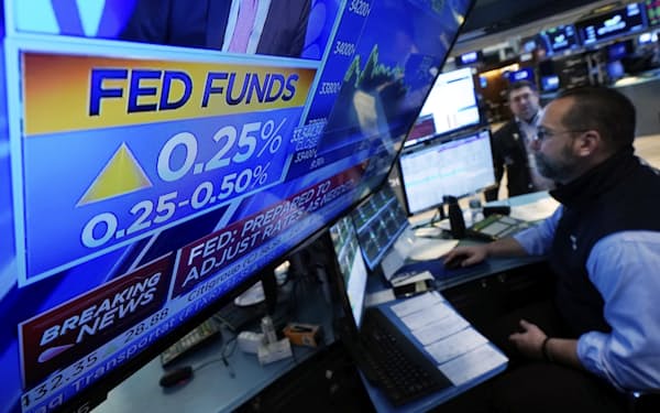 FRBの利上げ決定を報じるテレビ映像(16日、ニューヨーク証券取引所)=AP