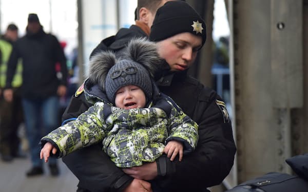 ウクライナからポーランドへ避難する人々が集まる駅で、子どもを抱える警察官（リビウ）＝ロイター