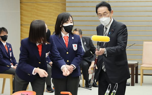 カーリング女子の選手から道具の説明を受ける岸田首相（18日、首相官邸）