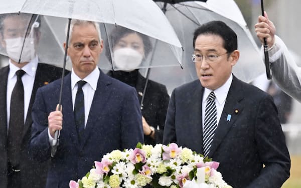 広島市を訪問し、平和記念公園の原爆慰霊碑に献花する岸田首相。左はエマニュエル駐日米大使（26日）＝共同
