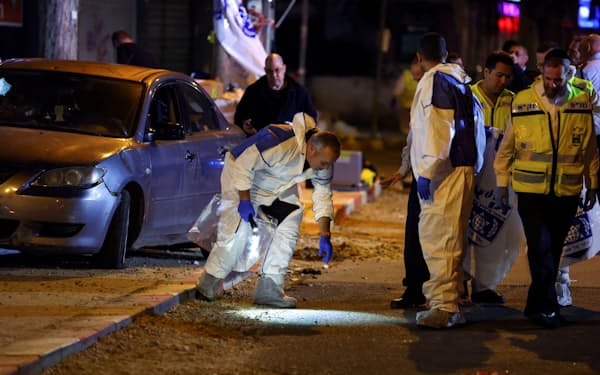 27日、イスラエル北部ハデラの銃撃現場を調べる警察当局者ら（ロイター＝共同）