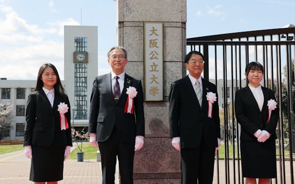 大阪公立大学の大学名看板を除幕し、笑顔を見せる辰巳砂学長（左から2人目）や新入生代表ら（1日午前、大阪市住吉区の杉本キャンパス）