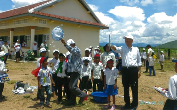 カンボジアに建設した校舎でシャボン玉を飛ばす筆者㊨と子供ら