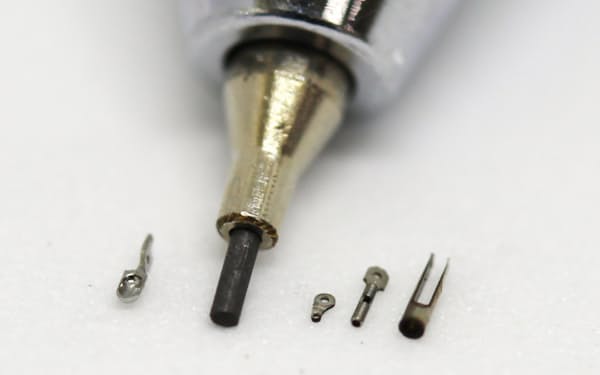 直径0.5ミリメートルの鉗子先端部品（シャープペン芯の左）と鉗子関連部品（同右）