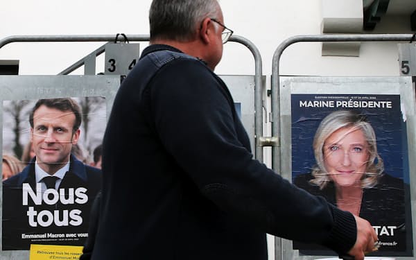 FILE - A man walks past presidential campaign posters of French President and centrist candidate for reelection Emmanuel Macron and French far-right presidential candidate Marine Le Pen in Anglet, southwestern France, Wednesday, April 8, 2022. President Emmanuel Macron may be ahead in the presidential race so far, but he warned his supporters that "nothing is done" and his runoff battle with far-right challenger Marine Le Pen will be a hard fight. (AP Photo/Bob Edme, File)
