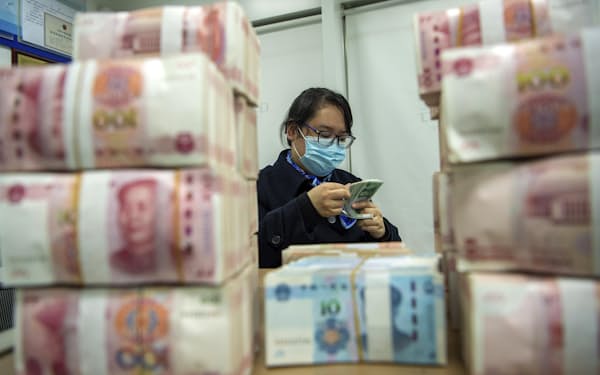 中国東部、江蘇省の銀行で人民元札を数える行員（2021年12月）＝ＡＰ