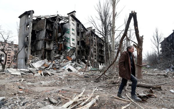 　17日、ウクライナ・マリウポリで破壊された建物の近くを歩く男性＝ロイター