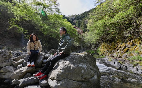 「MOKKI NO MORI」のフィールド内を流れる川で新緑の森を満喫する中山直之さん・三雅さん夫妻（４月、東京都檜原村）