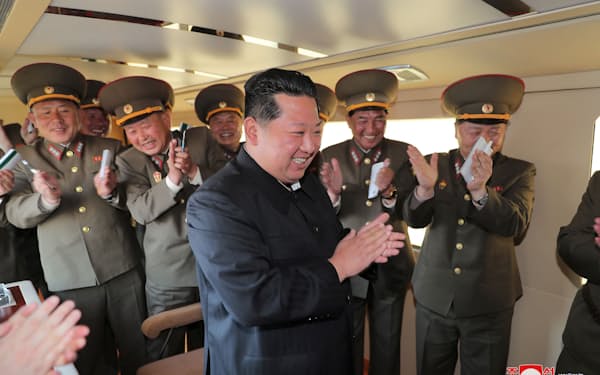 「新型戦術誘導兵器」の発射実験を視察し、拍手する北朝鮮の金正恩総書記（手前）＝朝鮮中央通信・ロイター