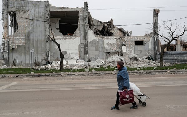 破壊された建物の前を歩く市民（１９日、マリウポリ）＝ロイター