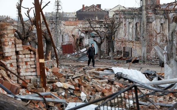 22日、ウクライナ・マリウポリで、破壊された建物の近くを歩く男性=ロイター