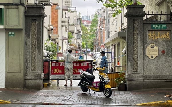 上海の居住区に防護服を着て荷物を届ける人（23日）=ロイター