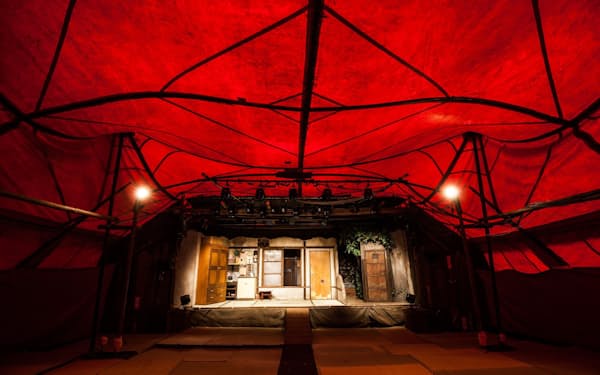 劇団唐組の紅テントの内部。奥の舞台で芝居が上演され、手前に観客が座る。さまざまな場所に移動可能な、広い意味での劇場だ©唐組