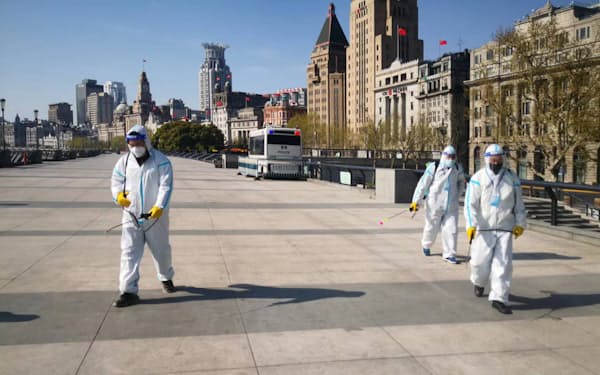 防護服を着て路上に消毒剤を散布する要員ら（18日、上海）＝ゲッティ共同