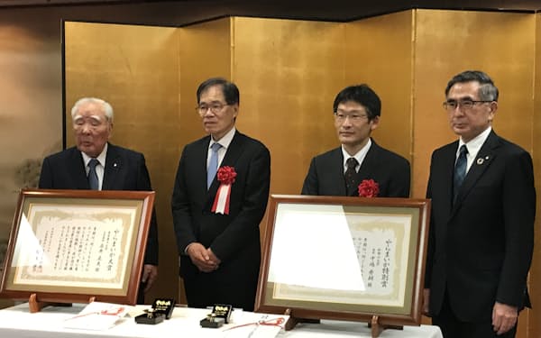 鈴木修理事長（写真左）が「大賞」の永井正夫・東京農工大名誉教授（中左）、「特別賞」の中嶋秀朗・和歌山大教授（中右）に賞状を授与した。右は鈴木俊宏評議員（スズキ社長）