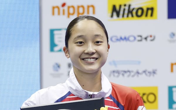 女子200メートル背泳ぎで初優勝し、表彰式で笑顔の成田実生（1日、横浜国際プール）＝共同