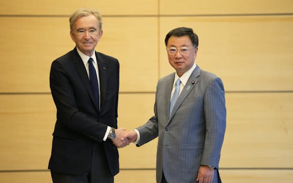 LVMH CEO Bernard Arnault, left, and Japanese Chief Cabinet Secretary Hirokazu Matsuno shake hands as they pose for a photo before their talk at the Prime Minister's Office of Japan in Tokyo, Monday, May 2, 2022. (AP Photo/Hiro Komae, Pool)