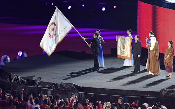 2018年9月、ジャカルタ・アジア大会の閉会式で、引き継がれた大会旗を振る中国・杭州の関係者＝共同