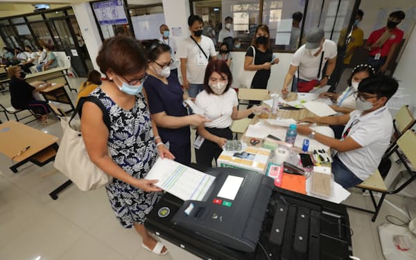 フィリピン大統領選の投票が始まり、投票所の専用端末を使って投票する有権者（９日午前、マニラ）＝小林健撮影
