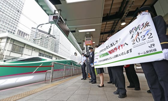 東北新幹線が完全復旧して通常ダイヤとなり、車両に向かって横断幕を掲げるJR東日本の社員ら（13日午前、JR東京駅）=共同