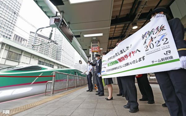 東北新幹線が完全復旧して通常ダイヤとなり、車両に向かって横断幕を掲げるJR東日本の社員ら(13日午前、JR東京駅)=共同