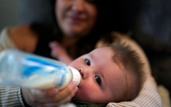 生後5カ月の息子に粉ミルクを与える女性（12日)＝AP