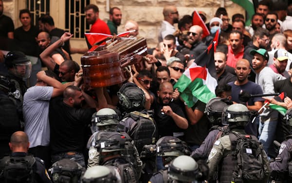 シリン・アブアクラさんの葬儀で棺を運ぶ弔問客に立ちはだかるイスラエルの警察=ロイター