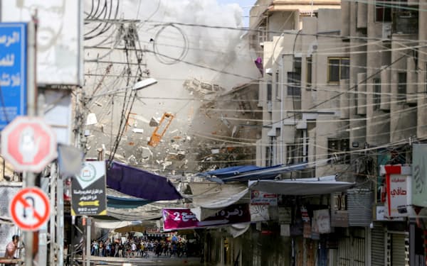 イスラエル軍の空爆で倒壊するガザ地区の建物（21年5月）=ロイター