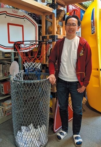 「仕掛学」を提唱する大阪大学の松村真宏教授。左にある「ゴミをついシュートしたくなるゴミ箱」などを考案
