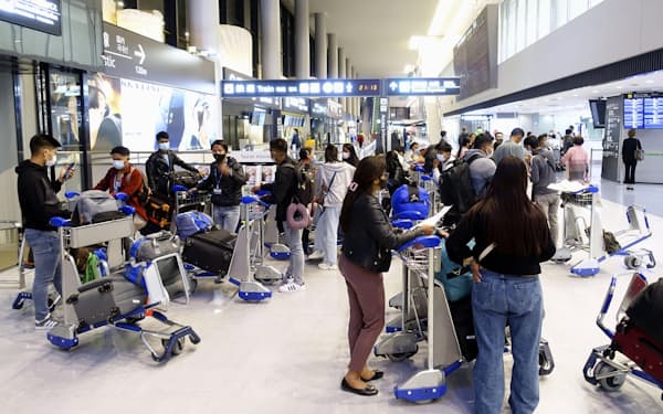 空港の到着ロビーに出て、検疫中の家族や友人を待つ入国者ら（4月、成田空港）=共同