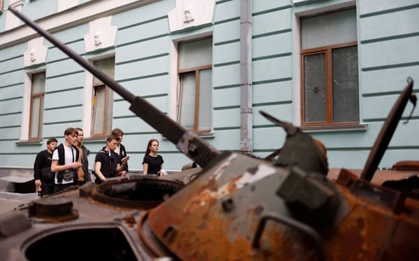 ウクライナの首都キーウ（キエフ）で、破壊され展示されたロシア軍戦車の脇を通る若者（20日）=ロイター