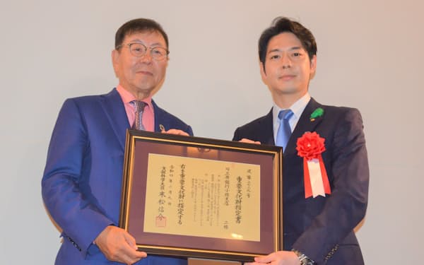 北海道の鈴木知事㊨がニトリHDの似鳥会長に指定書を手渡した（21日、北海道小樽市）