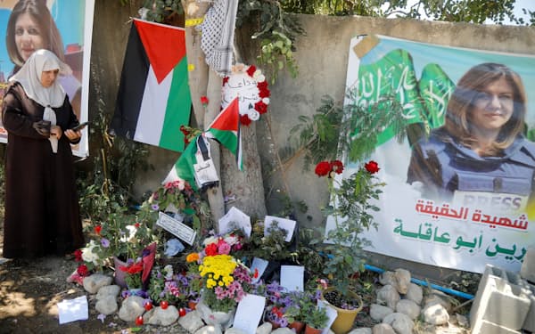 パレスチナ系米国人ジャーナリストのシリン・アブアクラ氏が銃弾を受けた場所で写真を撮る女性（17日、ヨルダン川西岸）＝ロイター