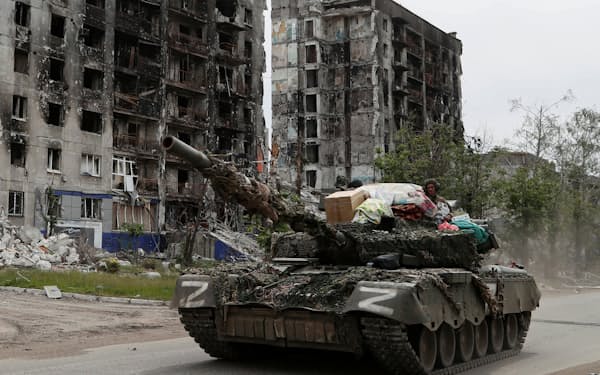 破壊された住宅の前を通る親ロシア派武装勢力の戦車（26日、ウクライナ東部ルガンスク州）＝ロイター